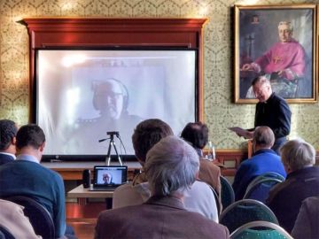 Foto van het symposium met Fred van Iersel op het scherm