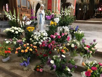 Bloemen bij Maria in de meimaand; dagelijks brengen mensen nieuwe bloemen